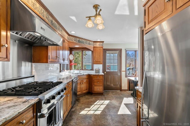 kitchen featuring under cabinet range hood, stainless steel appliances, tasteful backsplash, and brown cabinetry