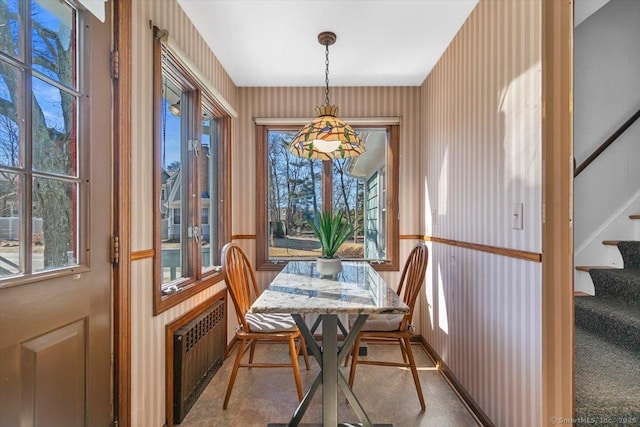 dining area with plenty of natural light, radiator, wallpapered walls, and stairs