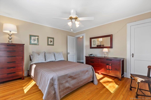 bedroom featuring ceiling fan, baseboards, crown molding, and light wood-style floors