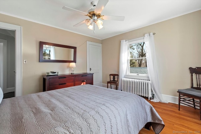 bedroom featuring ornamental molding, radiator heating unit, baseboards, and wood finished floors