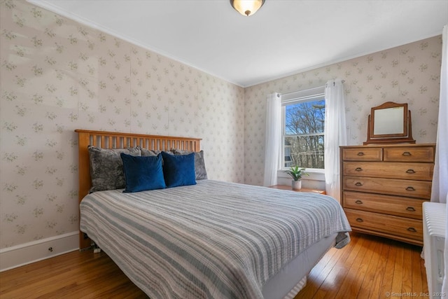 bedroom featuring radiator, baseboards, hardwood / wood-style flooring, and wallpapered walls