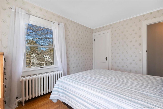 bedroom with light wood-type flooring, radiator heating unit, and wallpapered walls