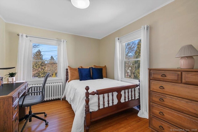 bedroom with light wood-style flooring, radiator, and crown molding