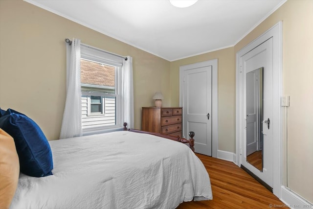 bedroom with crown molding, baseboards, and wood finished floors