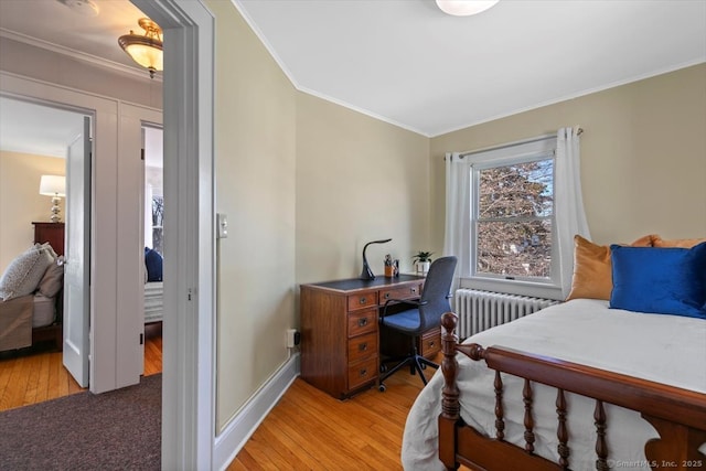 bedroom with crown molding, radiator, baseboards, and light wood finished floors