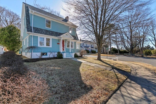 view of front of property featuring a shingled roof and a chimney