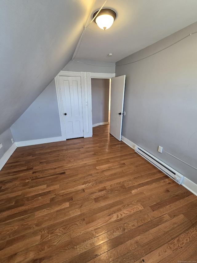 additional living space with a baseboard radiator, baseboards, wood finished floors, and vaulted ceiling