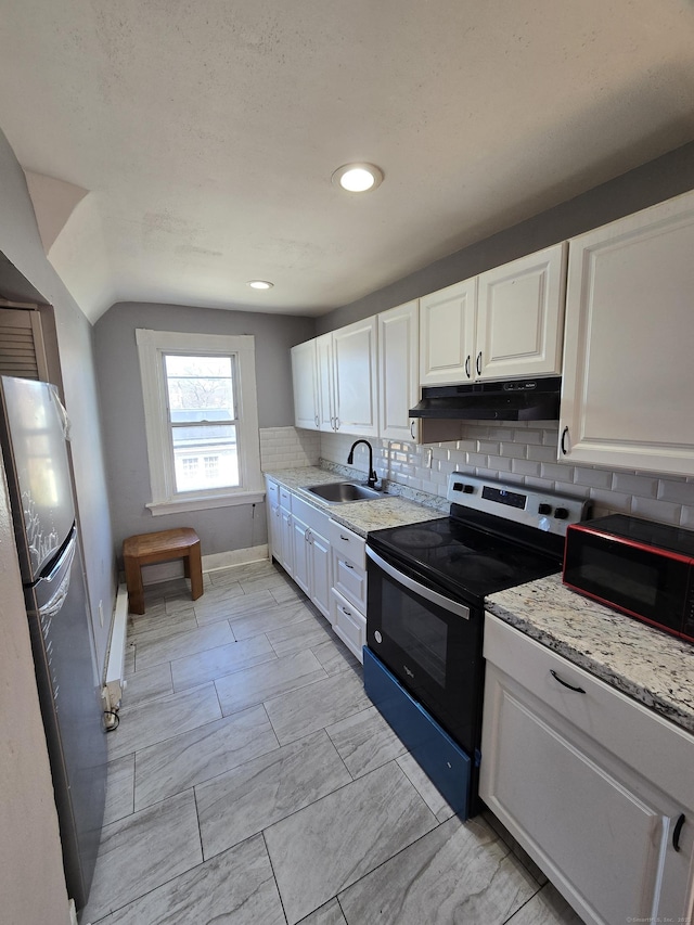 kitchen featuring tasteful backsplash, under cabinet range hood, range with electric stovetop, freestanding refrigerator, and a sink