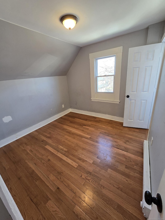 bonus room with dark wood finished floors, baseboard heating, baseboards, and lofted ceiling