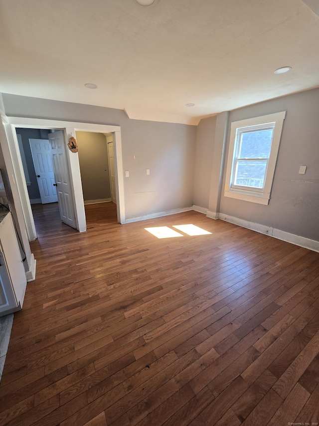 unfurnished room featuring baseboards and dark wood-style flooring