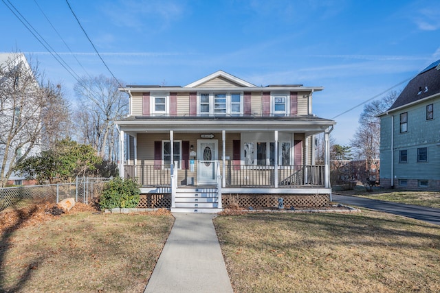 view of front facade with covered porch, a front yard, and fence