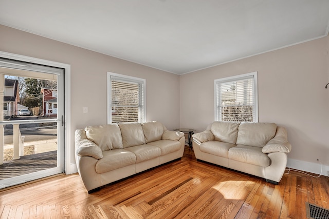 living area featuring visible vents, plenty of natural light, baseboards, and hardwood / wood-style flooring