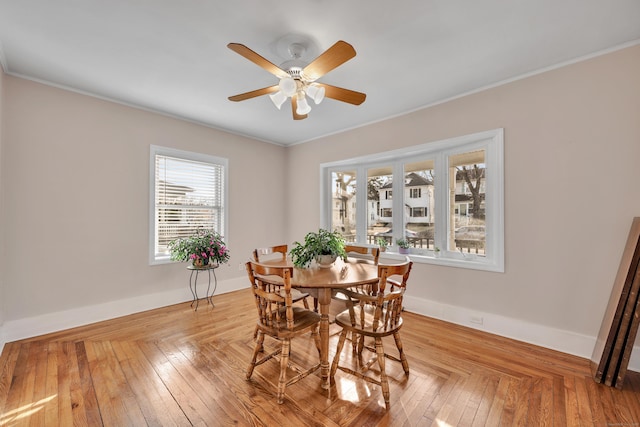 dining room with light wood finished floors, crown molding, and baseboards