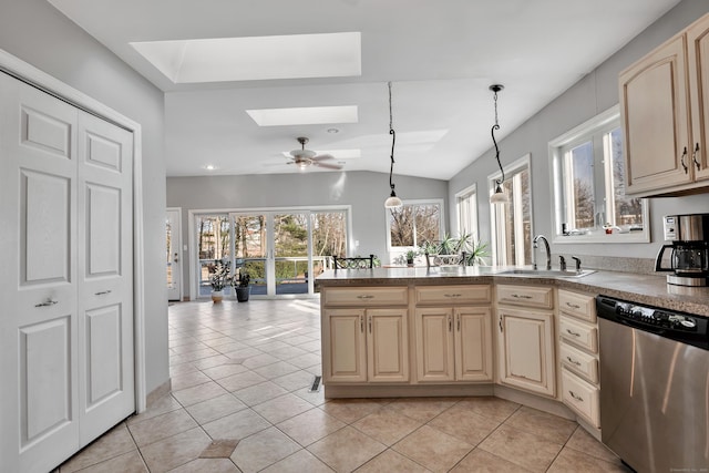 kitchen with light tile patterned floors, a sink, cream cabinetry, dishwasher, and lofted ceiling with skylight