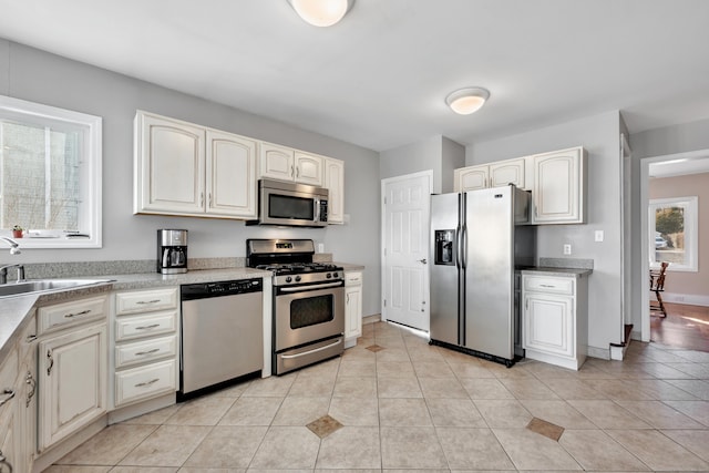 kitchen with light tile patterned floors, stainless steel appliances, light countertops, and a sink