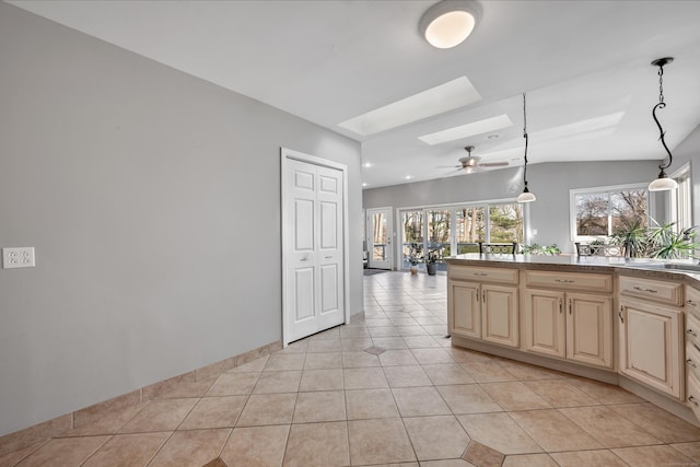 kitchen featuring light tile patterned floors, vaulted ceiling with skylight, ceiling fan, cream cabinets, and decorative light fixtures