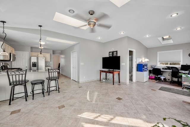 kitchen featuring lofted ceiling with skylight, a kitchen breakfast bar, a peninsula, stainless steel appliances, and a ceiling fan