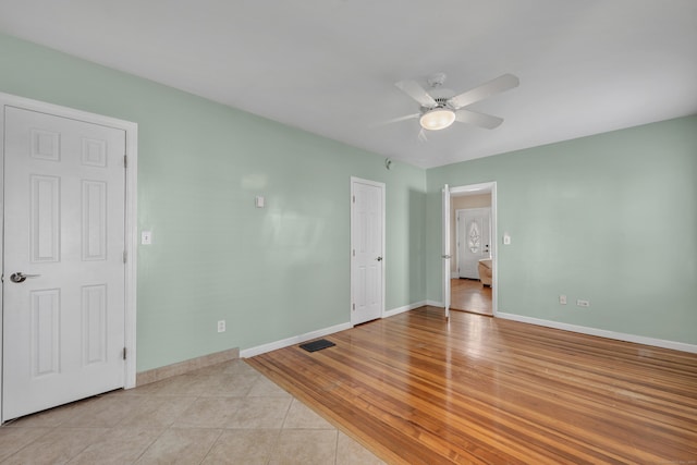 unfurnished bedroom featuring light wood finished floors, visible vents, a ceiling fan, and baseboards