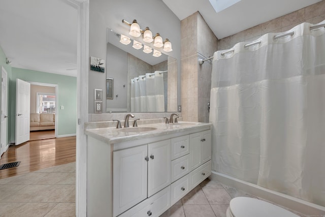 bathroom featuring a sink, a skylight, double vanity, and tile patterned flooring