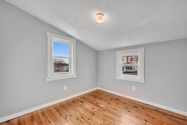 spare room with cooling unit, baseboards, lofted ceiling, wood-type flooring, and a textured ceiling