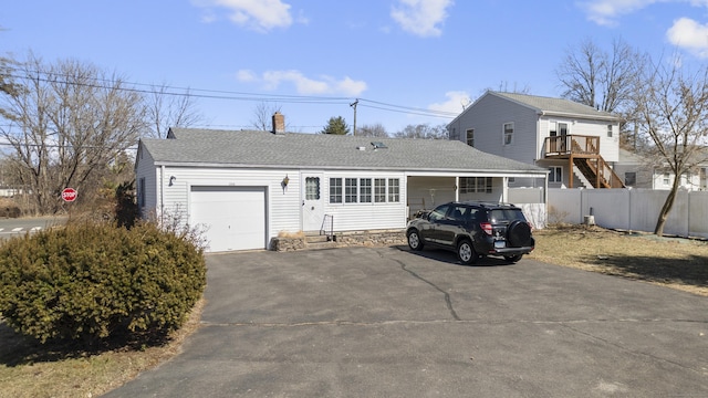 view of front facade with driveway, roof with shingles, a garage, and fence