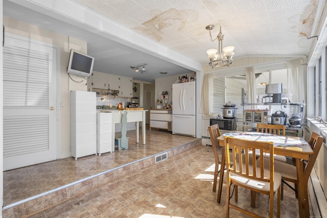 dining space featuring visible vents, a notable chandelier, and vaulted ceiling