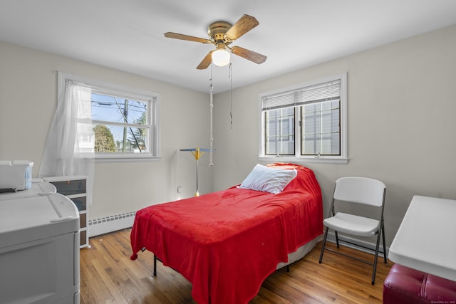 bedroom featuring wood finished floors, baseboard heating, and ceiling fan