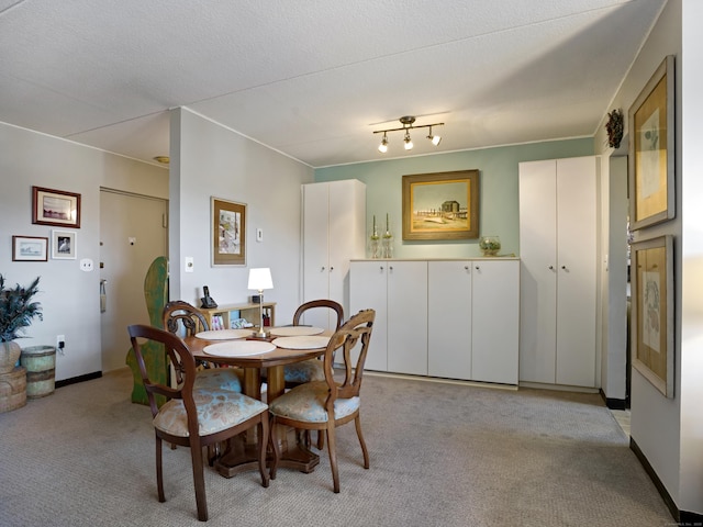 dining room with baseboards, light carpet, and a textured ceiling