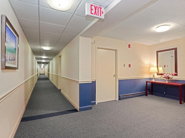 hall featuring carpet flooring and a paneled ceiling