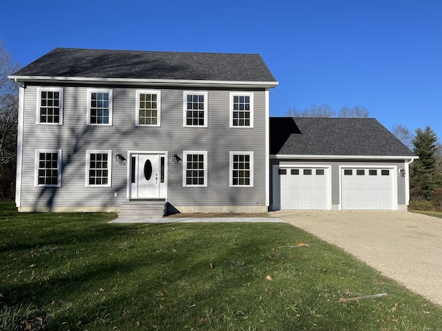 colonial-style house with entry steps, an attached garage, a front lawn, and concrete driveway