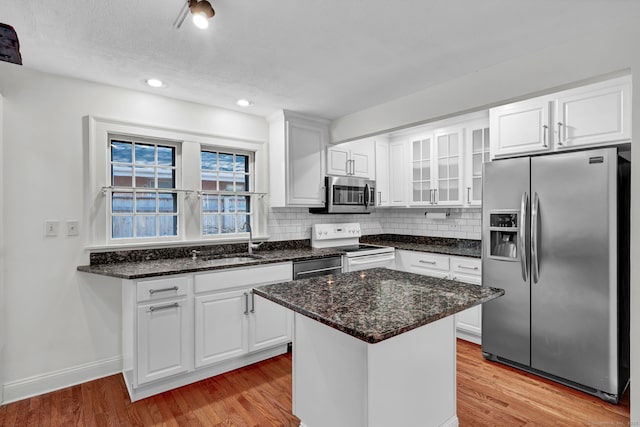 kitchen featuring backsplash, light wood-type flooring, appliances with stainless steel finishes, and a sink