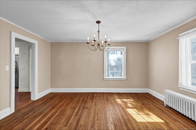 spare room with dark wood-type flooring, radiator heating unit, and an inviting chandelier