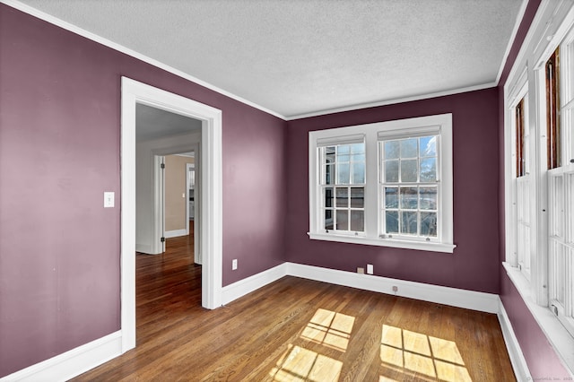 unfurnished room with crown molding, wood finished floors, baseboards, and a textured ceiling