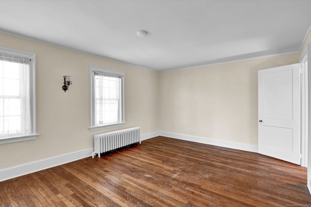 spare room featuring dark wood finished floors, radiator heating unit, and baseboards