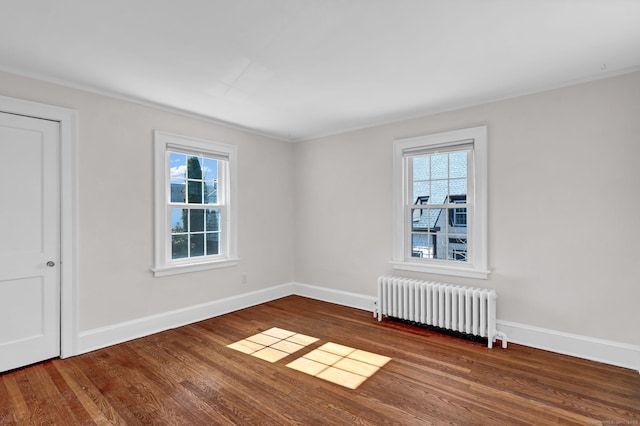 unfurnished room with a healthy amount of sunlight, radiator, baseboards, and wood finished floors