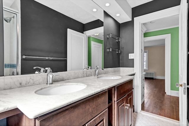 full bathroom featuring double vanity, radiator heating unit, baseboards, and a sink