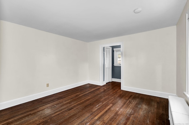 spare room featuring baseboards and dark wood-style flooring