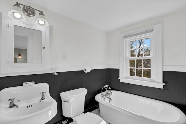 full bathroom with a sink, a freestanding bath, and toilet