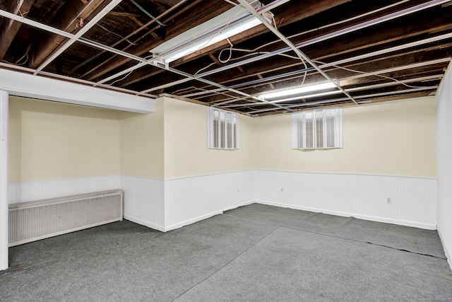 finished basement featuring radiator heating unit and wainscoting