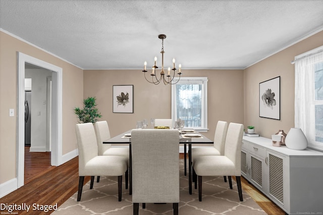 dining area featuring wood finished floors, a textured ceiling, a chandelier, and crown molding