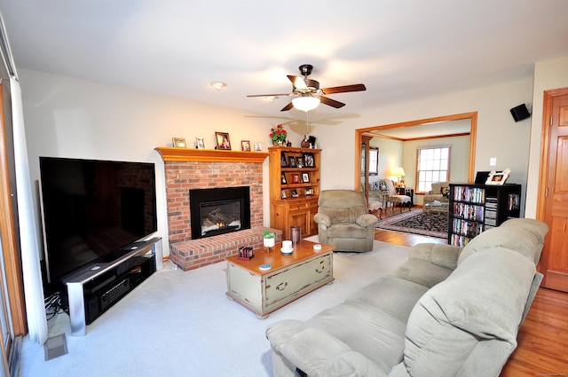 living area featuring visible vents, a brick fireplace, wood finished floors, and a ceiling fan