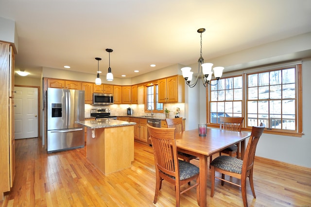 kitchen featuring a kitchen island, a notable chandelier, appliances with stainless steel finishes, and light wood finished floors