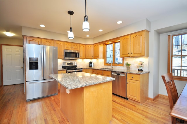 kitchen with a sink, light wood-style flooring, light stone countertops, and stainless steel appliances