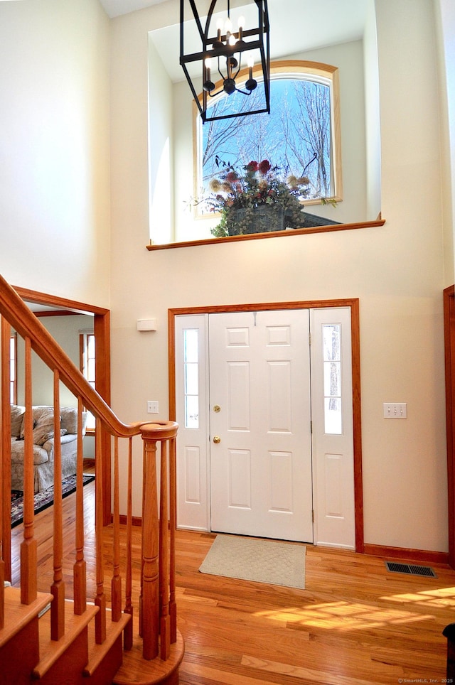 foyer entrance featuring visible vents, plenty of natural light, a notable chandelier, and a high ceiling