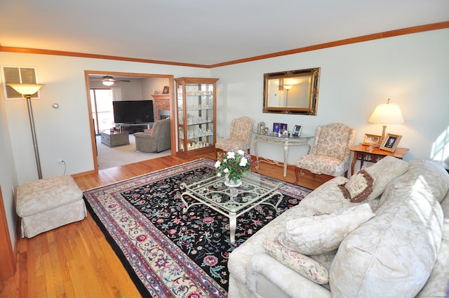 living area with a ceiling fan, wood finished floors, and crown molding