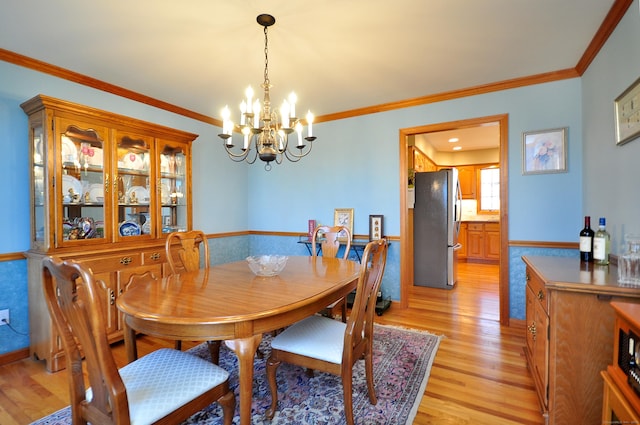 dining room featuring an inviting chandelier, light wood-type flooring, and ornamental molding