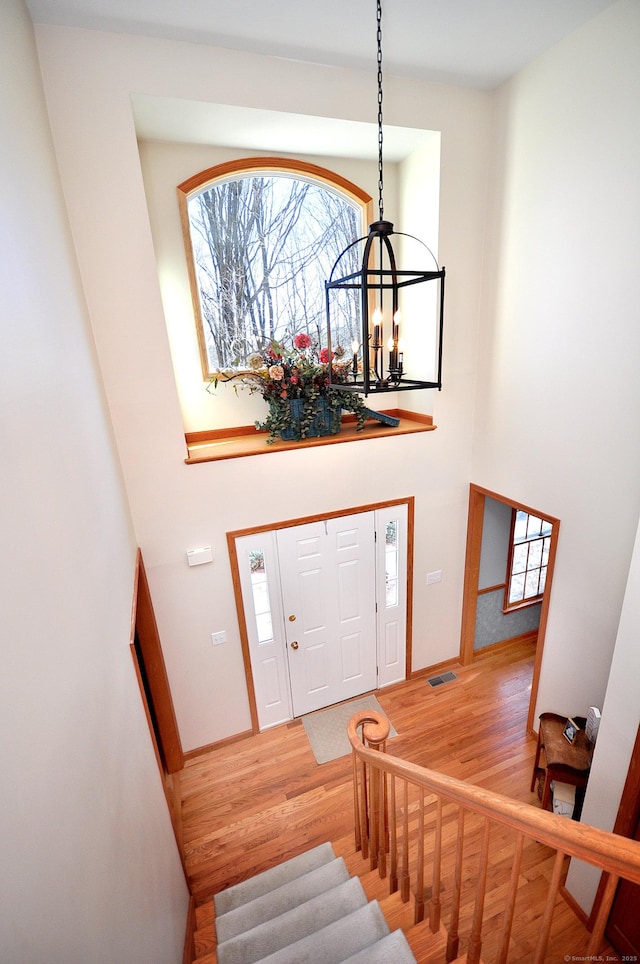 foyer with visible vents, an inviting chandelier, wood finished floors, and stairs