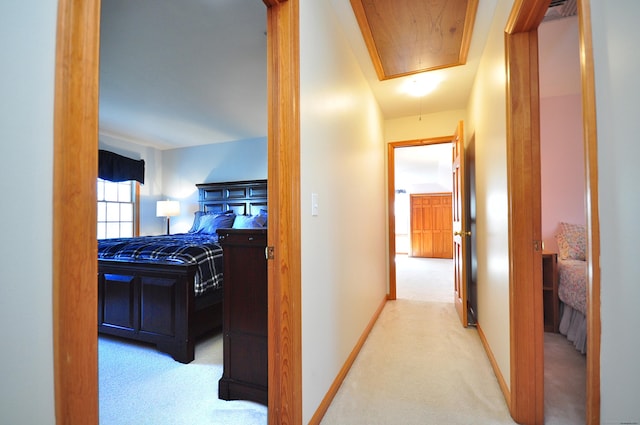 corridor featuring attic access, carpet flooring, and baseboards