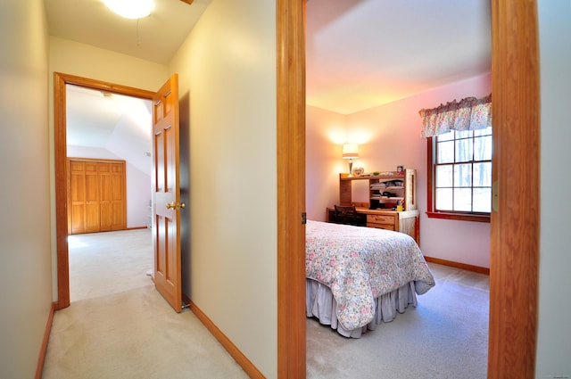 hallway with baseboards, light colored carpet, and lofted ceiling