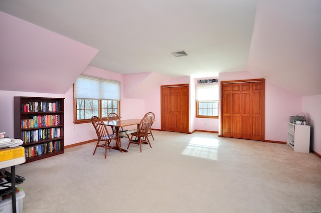 dining room with lofted ceiling, light colored carpet, visible vents, and a wealth of natural light